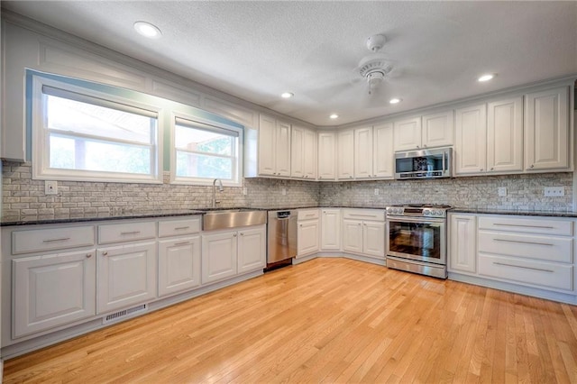 kitchen featuring light hardwood / wood-style flooring, appliances with stainless steel finishes, sink, white cabinetry, and ceiling fan