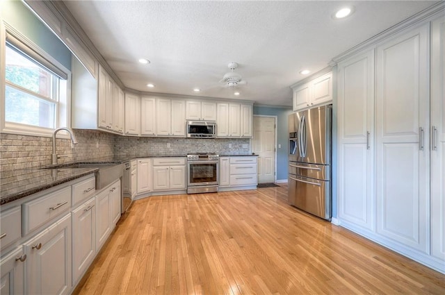 kitchen with light hardwood / wood-style flooring, appliances with stainless steel finishes, sink, white cabinetry, and ceiling fan