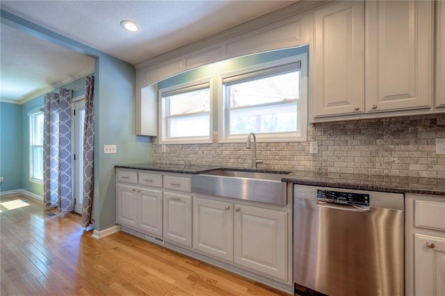 kitchen featuring dishwasher, white cabinets, sink, light wood-type flooring, and dark stone counters