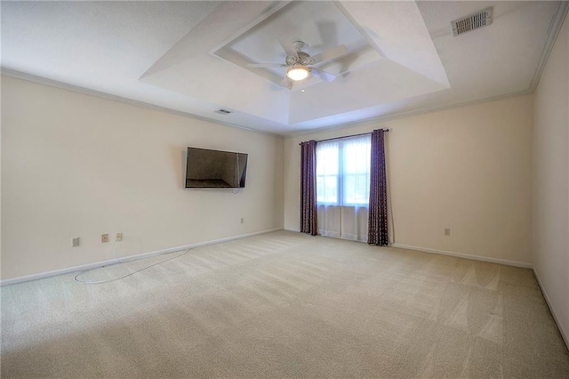 carpeted spare room with ceiling fan, ornamental molding, and a tray ceiling