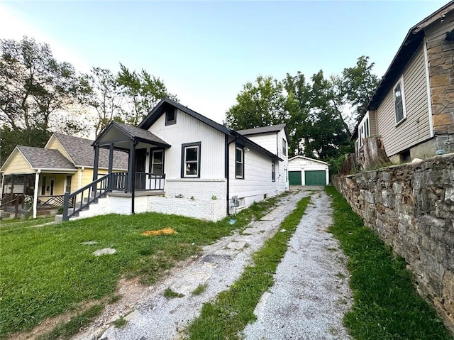 view of property exterior featuring a lawn, covered porch, an outbuilding, and a garage