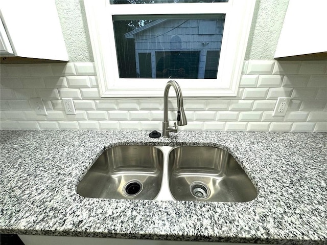 interior details with sink, white cabinets, stone counters, and tasteful backsplash