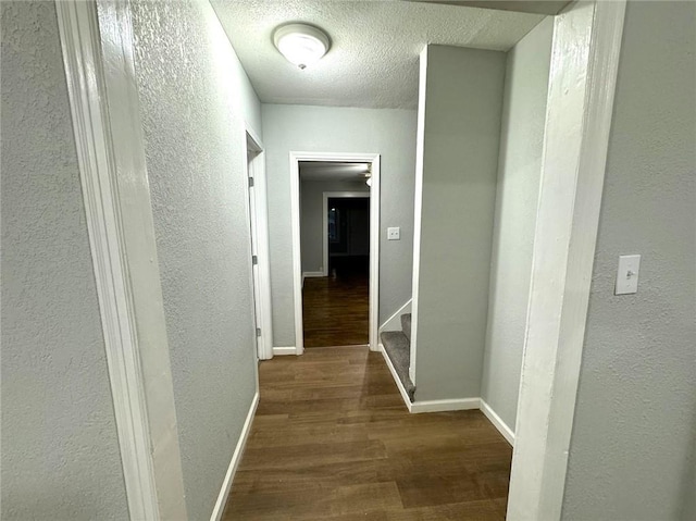 hall with a textured ceiling and wood-type flooring