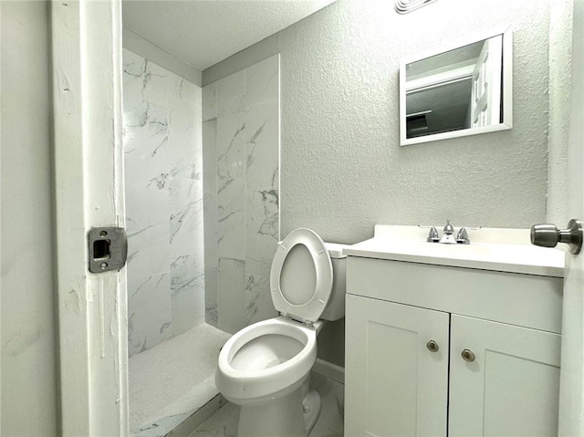 bathroom featuring vanity, tile patterned floors, a textured ceiling, a tile shower, and toilet