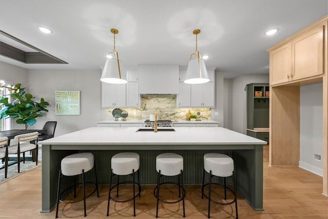 8720 N Lewis Ave, Kansas City, MO 64157 - kitchen featuring tasteful backsplash, light countertops, a kitchen island with sink, light wood finished floors, and recessed lighting