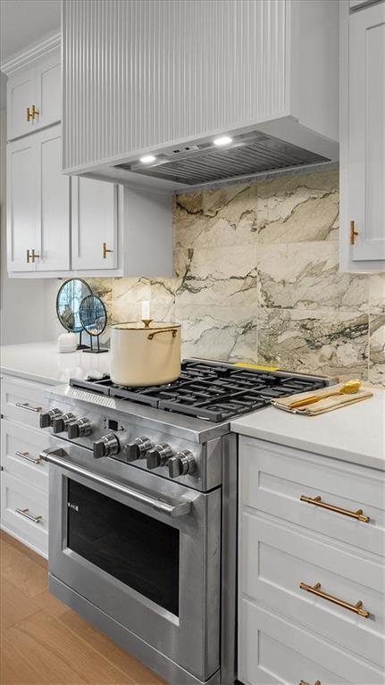 8720 N Lewis Ave, Kansas City, MO 64157 - kitchen featuring high end stainless steel range, wall chimney range hood, white cabinets, decorative backsplash, and light countertops