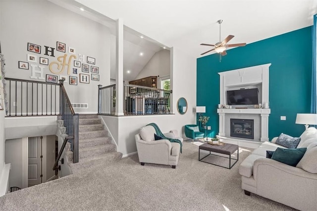 carpeted living room with ceiling fan and high vaulted ceiling