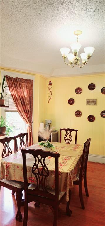 dining area featuring a textured ceiling, a chandelier, and hardwood / wood-style flooring