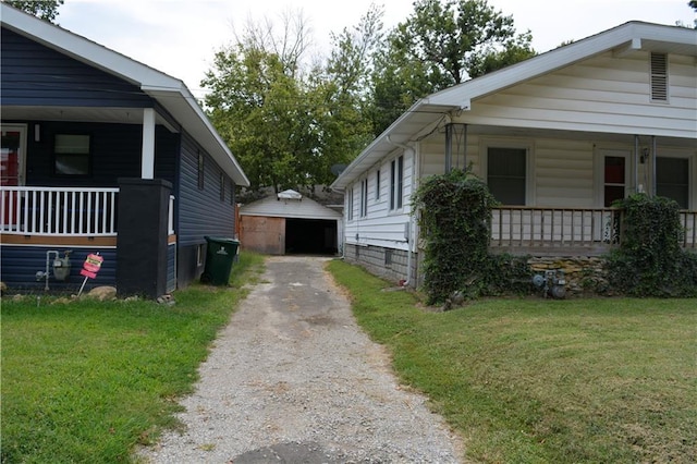 view of side of home with a garage, an outbuilding, covered porch, and a yard