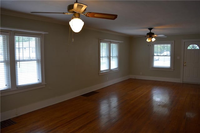 unfurnished room with baseboards, visible vents, crown molding, and wood finished floors