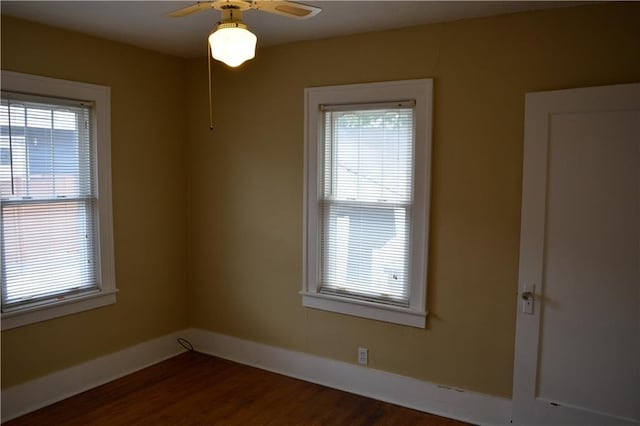 empty room featuring dark wood-style floors, plenty of natural light, and baseboards