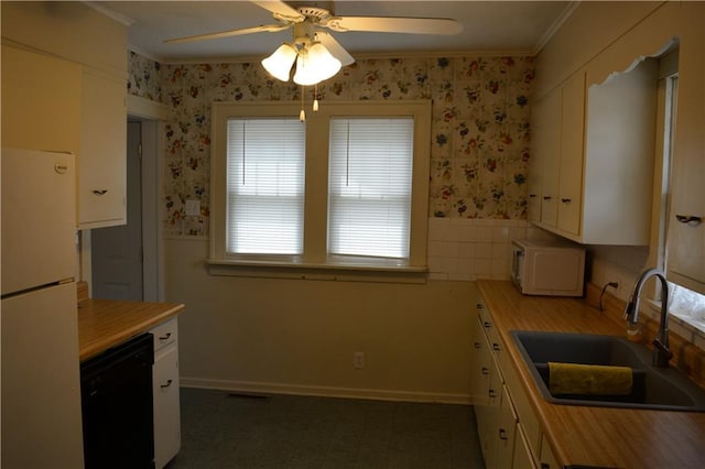 kitchen featuring white appliances, a sink, wainscoting, wallpapered walls, and crown molding