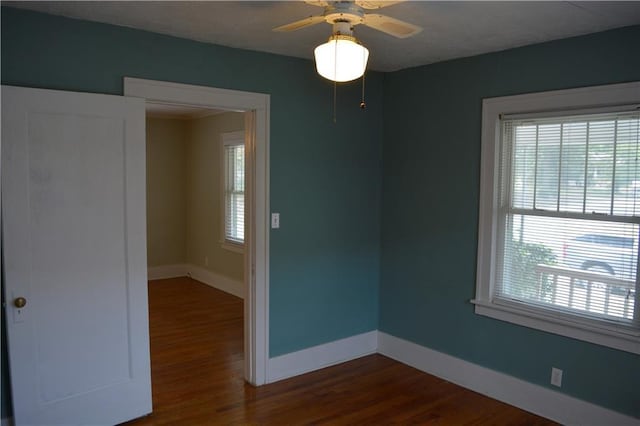 empty room with dark wood-style flooring, ceiling fan, and baseboards