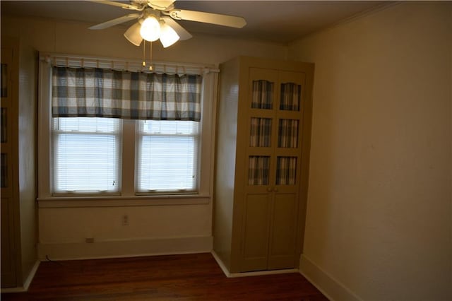 unfurnished dining area with ceiling fan, baseboards, dark wood-style flooring, and ornamental molding