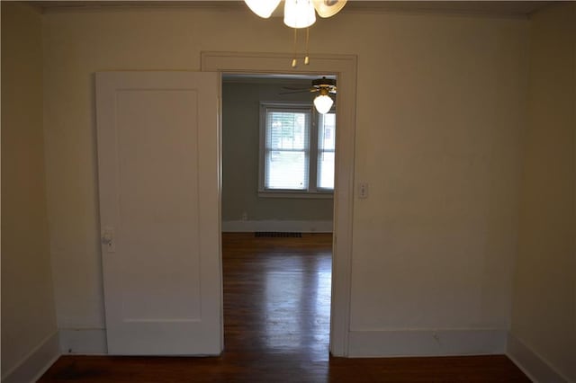 spare room with ornamental molding, dark wood-type flooring, visible vents, and baseboards