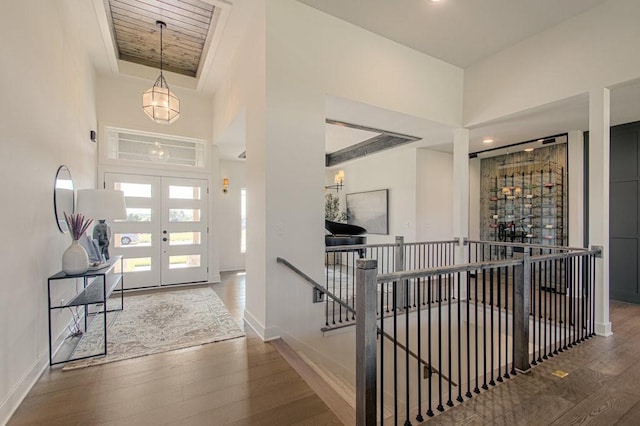 foyer entrance with hardwood / wood-style flooring, a towering ceiling, and french doors