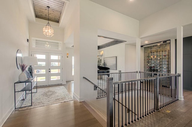 foyer entrance with a tray ceiling, french doors, baseboards, and wood finished floors