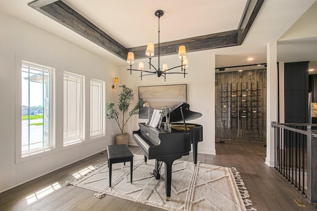 living area with a chandelier, a raised ceiling, baseboards, and wood finished floors