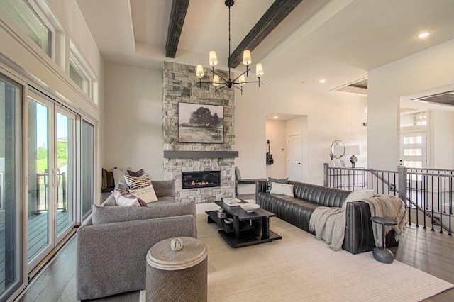 living area featuring beamed ceiling, a fireplace, wood finished floors, and an inviting chandelier