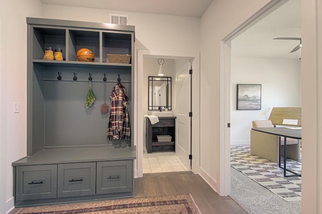 mudroom with visible vents, dark wood-type flooring, a ceiling fan, and baseboards