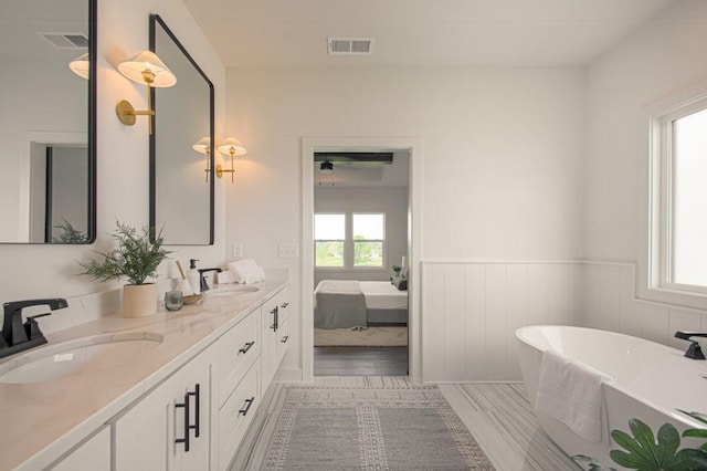 bathroom featuring a wainscoted wall, a sink, visible vents, and a healthy amount of sunlight