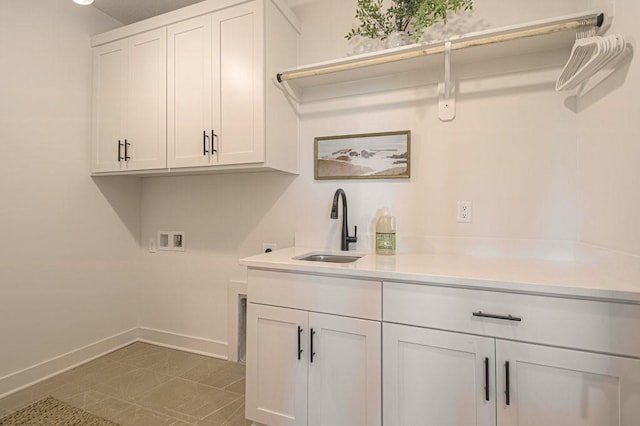 clothes washing area with hookup for a washing machine, cabinet space, baseboards, and a sink