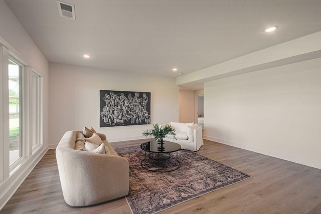 living room with baseboards, wood finished floors, visible vents, and recessed lighting