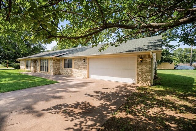 single story home featuring an attached garage, driveway, a front lawn, and brick siding