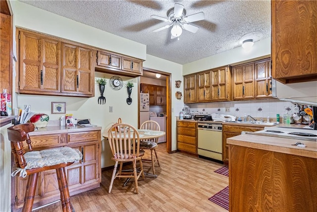 kitchen with decorative backsplash, light wood-type flooring, a textured ceiling, white appliances, and ceiling fan