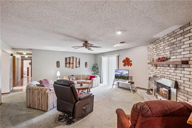 living room featuring ceiling fan, light colored carpet, a textured ceiling, and a fireplace