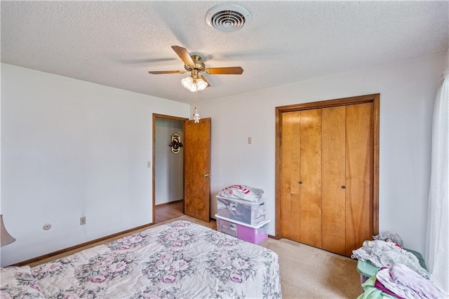 carpeted bedroom with a textured ceiling, a closet, and ceiling fan