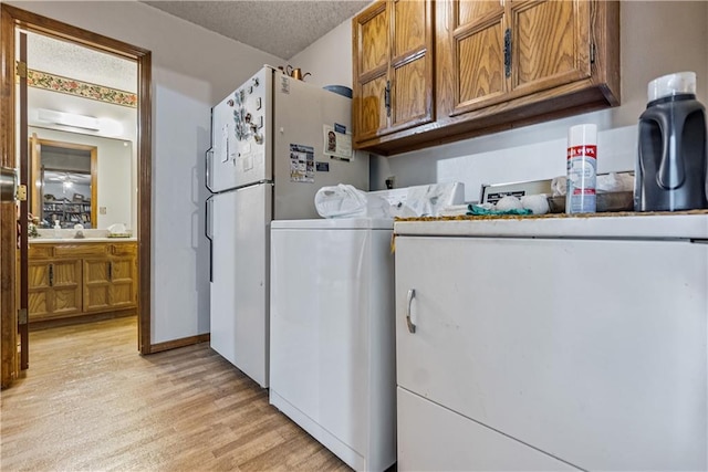 clothes washing area featuring washer / clothes dryer, a textured ceiling, and light hardwood / wood-style flooring