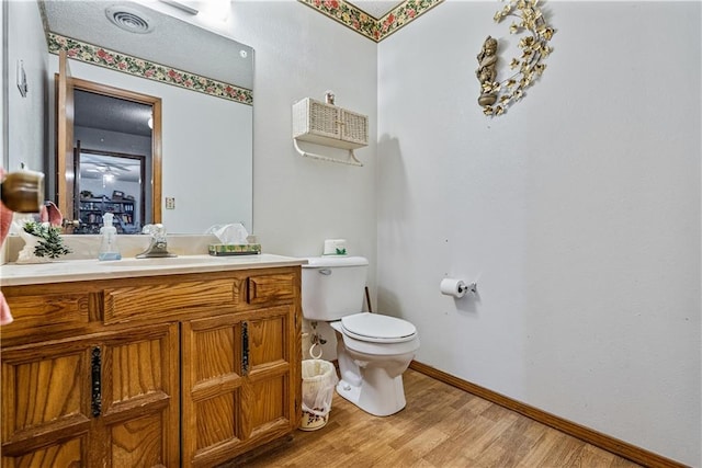 bathroom featuring wood-type flooring, toilet, and vanity