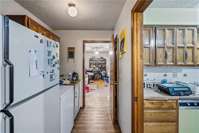 hall with a textured ceiling, washer / dryer, and hardwood / wood-style floors