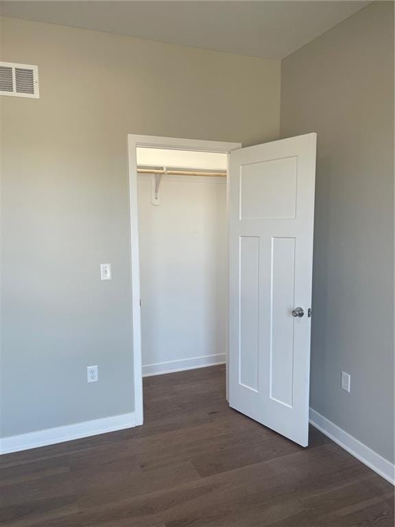 unfurnished bedroom featuring dark wood-type flooring and a closet