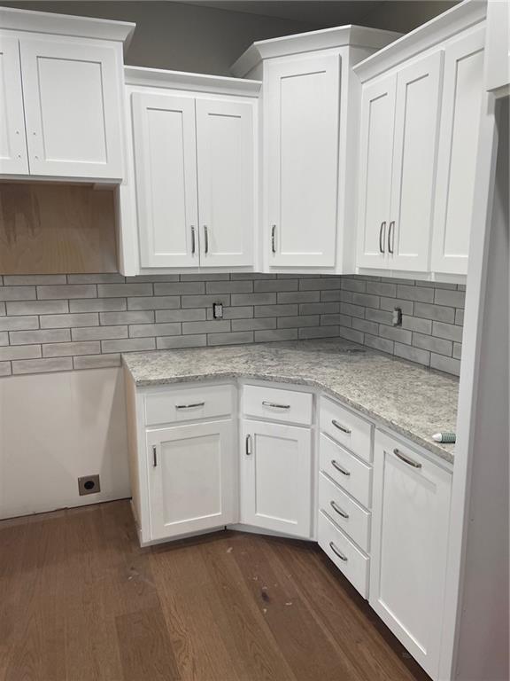 kitchen featuring white cabinetry, light stone counters, dark hardwood / wood-style floors, and decorative backsplash