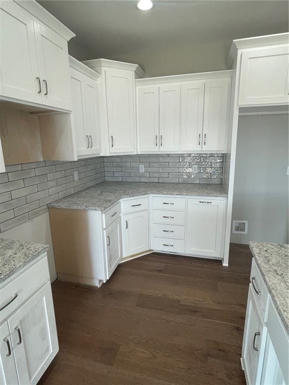 kitchen featuring tasteful backsplash, light stone countertops, dark hardwood / wood-style floors, and white cabinets