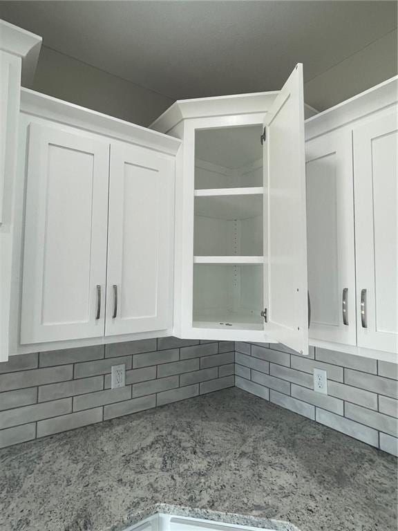 details with white cabinetry, light stone counters, and tasteful backsplash