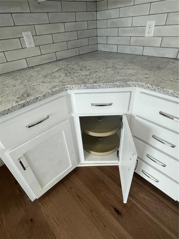 details with light stone countertops, white cabinets, and dark hardwood / wood-style flooring