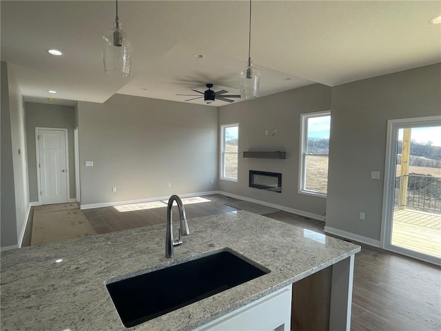 kitchen featuring light stone countertops, sink, dark wood-type flooring, and decorative light fixtures