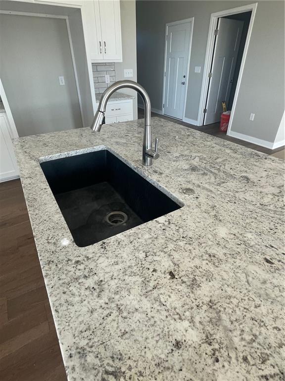 kitchen featuring light stone countertops, sink, and white cabinets