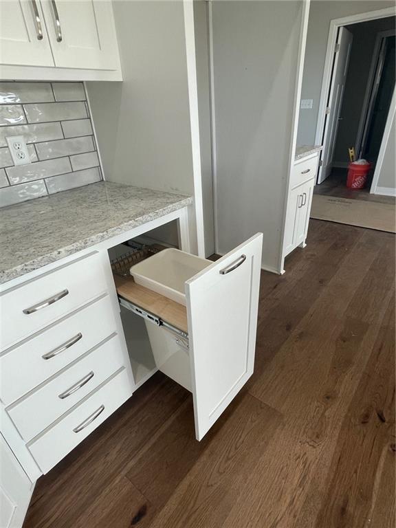 kitchen featuring white cabinetry, dark hardwood / wood-style flooring, light stone countertops, and tasteful backsplash