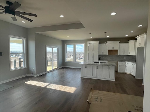 kitchen featuring white cabinetry, a kitchen island with sink, sink, and decorative light fixtures