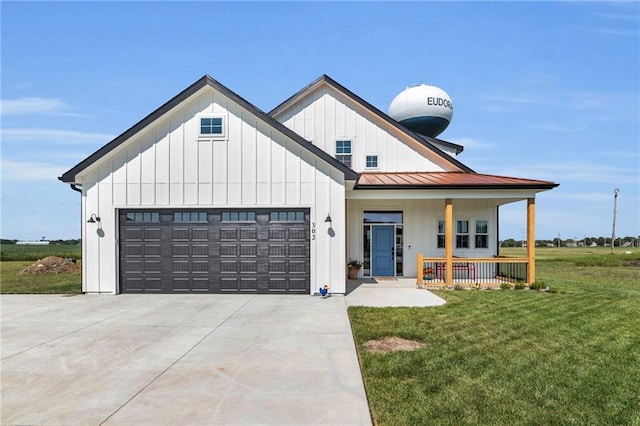 modern inspired farmhouse featuring a garage, a front yard, and covered porch