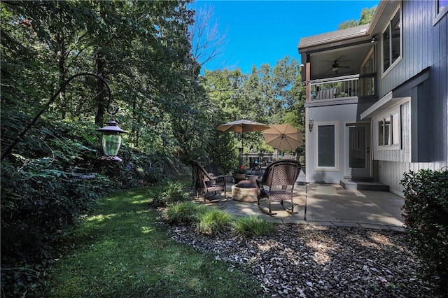 view of yard featuring ceiling fan, a balcony, and a patio