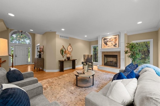 living room with a tiled fireplace, light hardwood / wood-style floors, and ornamental molding