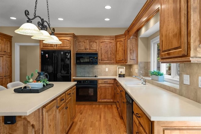 kitchen with sink, black appliances, light hardwood / wood-style flooring, a center island, and hanging light fixtures