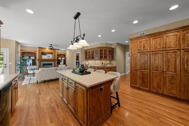 kitchen with a kitchen breakfast bar, stainless steel dishwasher, pendant lighting, light hardwood / wood-style flooring, and a center island