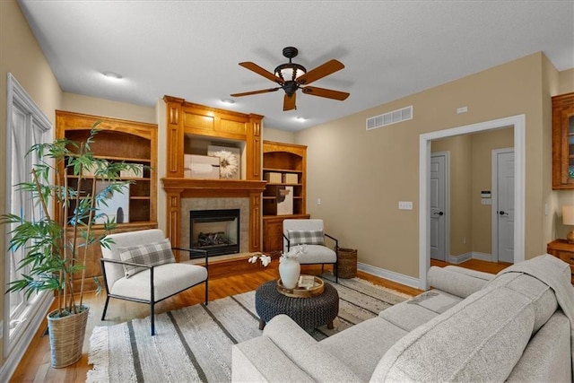 living room featuring ceiling fan, light hardwood / wood-style floors, and a fireplace