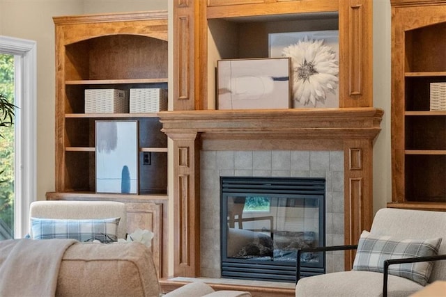 living area with a tile fireplace and built in features